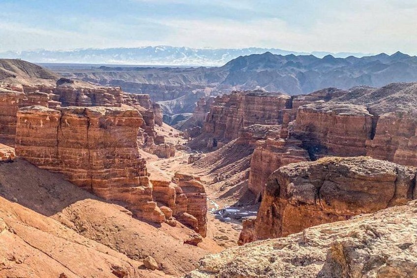 Un cañón con formaciones rocosas estratificadas y montañas nevadas a lo lejos. 5
