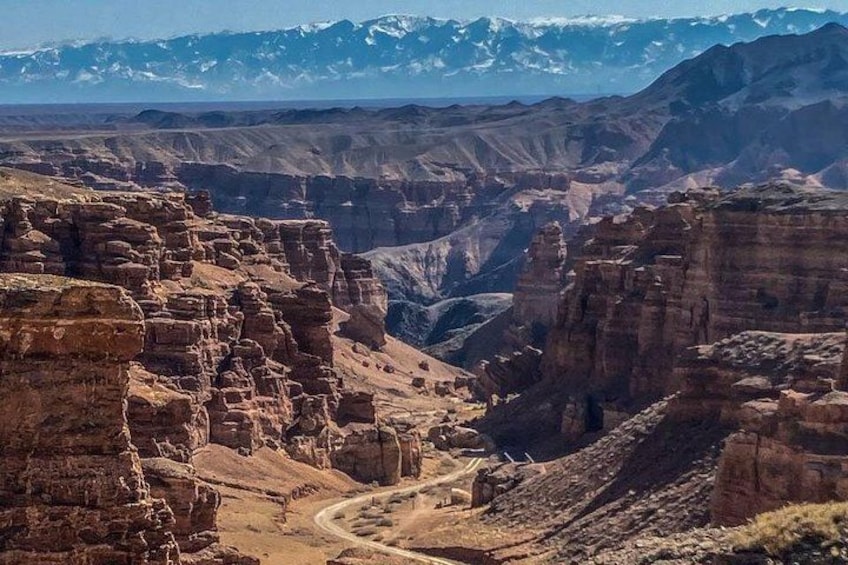 Un cañón con formaciones rocosas estratificadas y una carretera serpenteante. 2