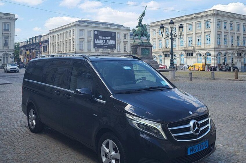 A black Mercedes-Benz SUV parked on a cobblestone street with a statue and a building in the background. 3