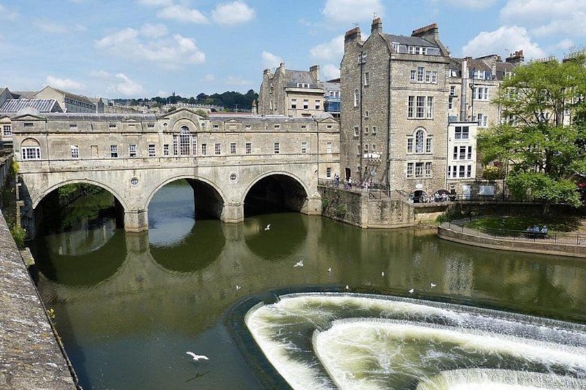 Un ponte di pietra su un fiume, con archi, un edificio con una torre e un albero. 4