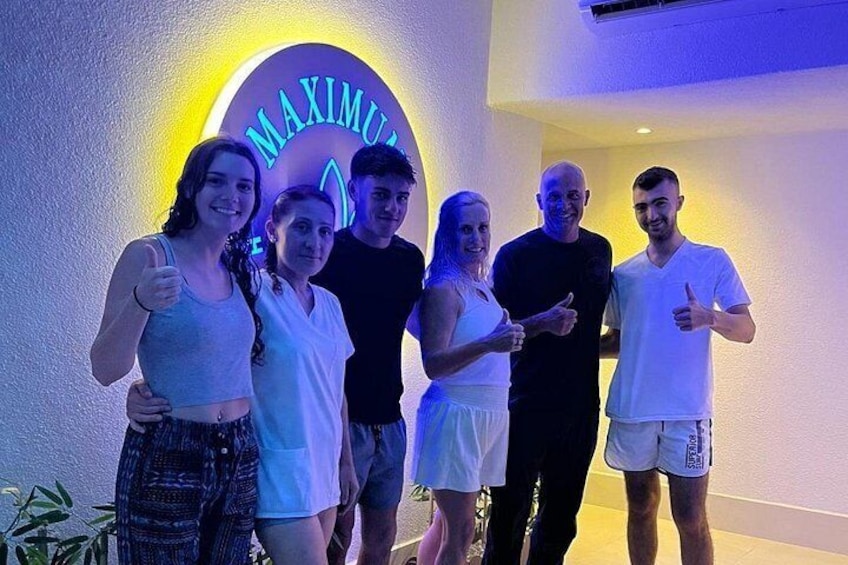 A group of people standing in front of a neon sign that reads 'MAXIMUS.' 3