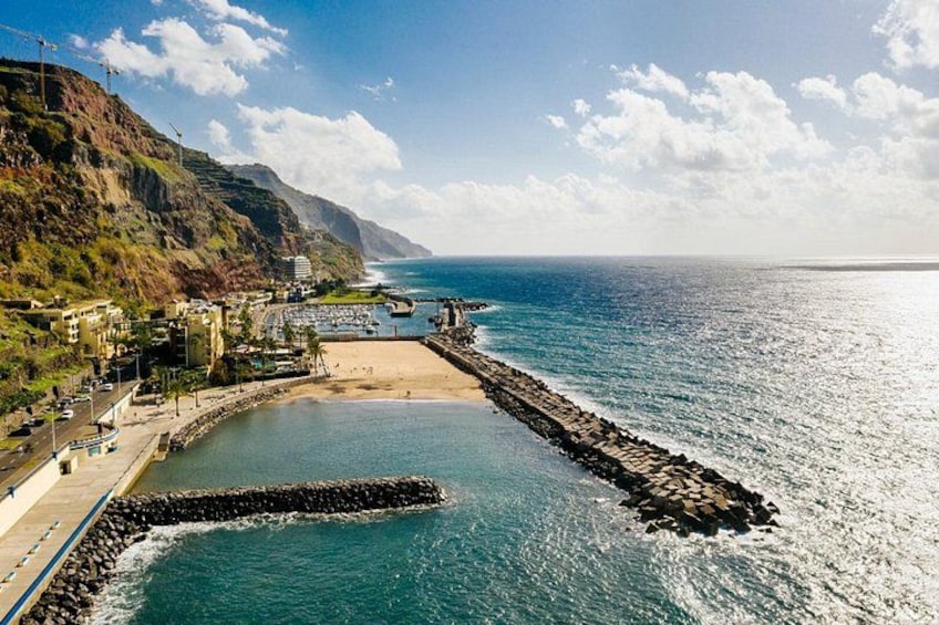 A coastal town with a beach, rocky breakwater, and buildings along the shore. 5