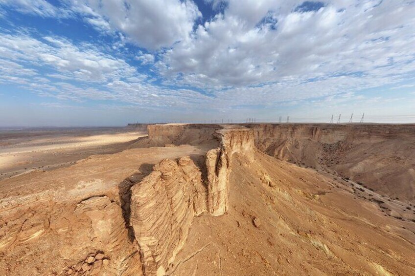 Weite Wüstenlandschaft mit einer markanten Klippe und Stromleitungen in der Ferne. 3