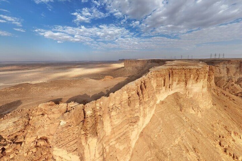 Weite Wüstenlandschaft mit einer markanten Klippe und Stromleitungen in der Ferne. 4