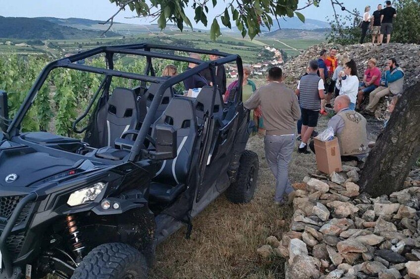 A black off-road vehicle parked on a rocky hillside with people gathered around. 5