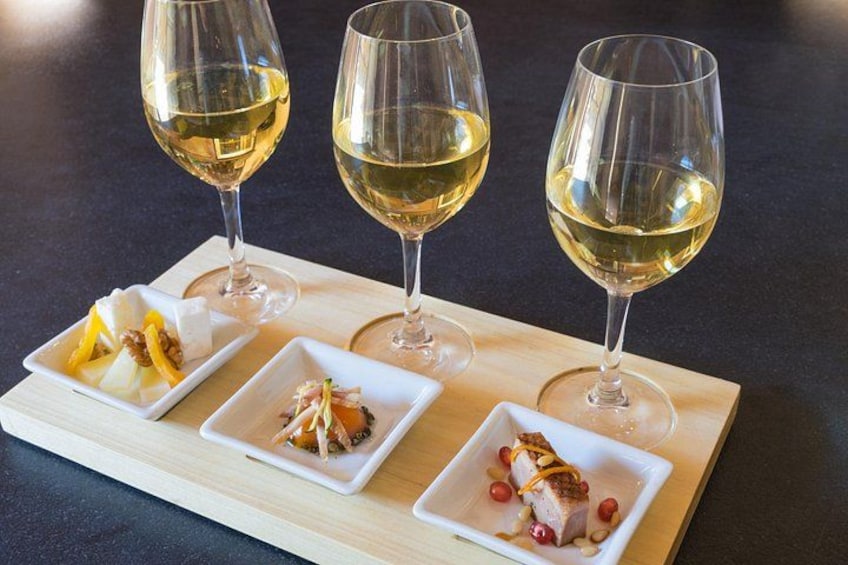 Three wine glasses and four square dishes with food on a wooden board. 2
