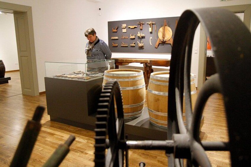 Une exposition de musée présentant des tonneaux en bois et un grand mécanisme à engrenages. 4