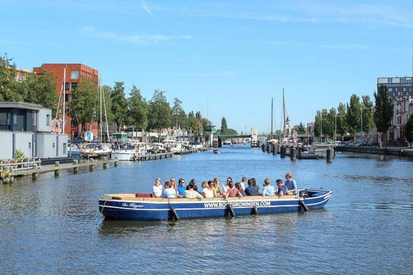 Ein Boot mit Passagieren auf einem Kanal, umgeben von Gebäuden und Bäumen. 5