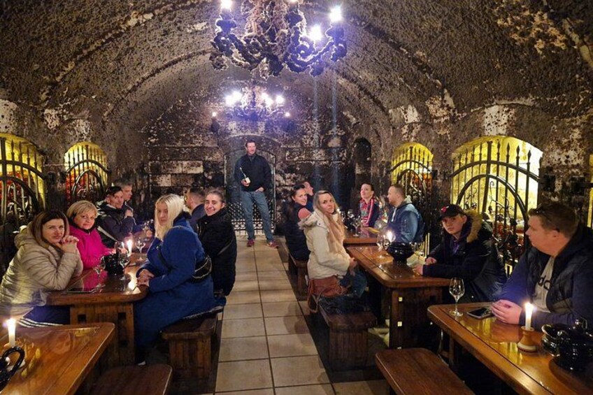 Un grupo de personas cenando en un restaurante tipo cueva, con paredes de piedra y candelabros. 4