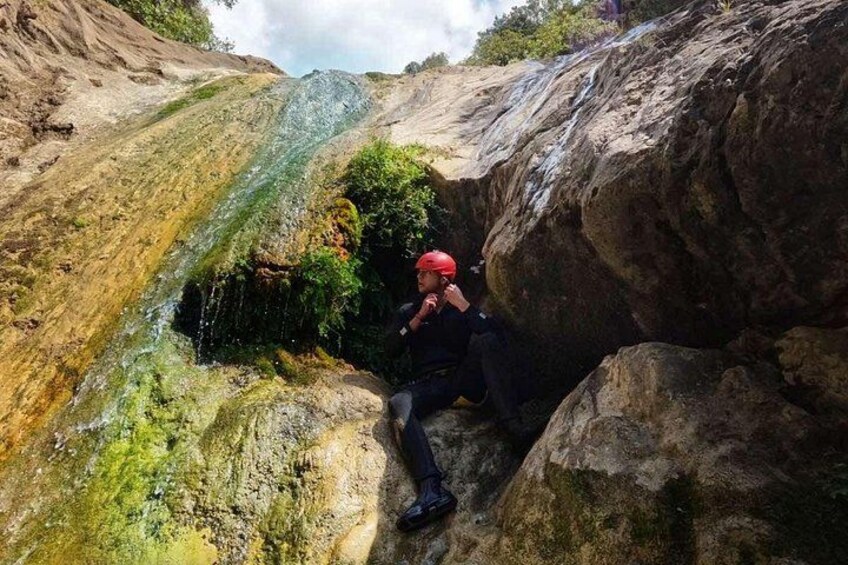 Iemand zit op een rots bij een waterval. 4