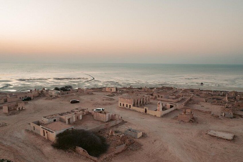 An aerial view of an ancient settlement with ruins and a beach in the background. 2