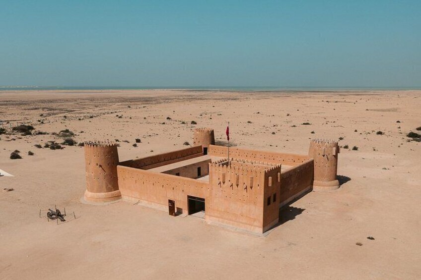 A desert landscape with a large, ancient stone structure featuring cylindrical towers and a flag. 3