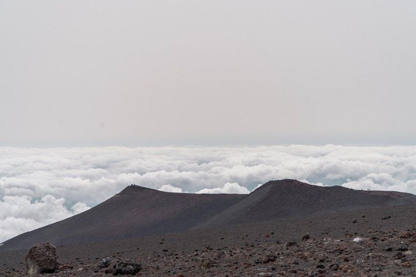 A volcanic landscape with two prominent peaks and a layer of clouds below. 3