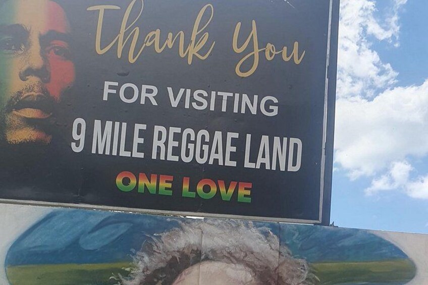 A sign with a message thanking visitors for visiting 9 Mile Reggae Land and promoting one love. 1