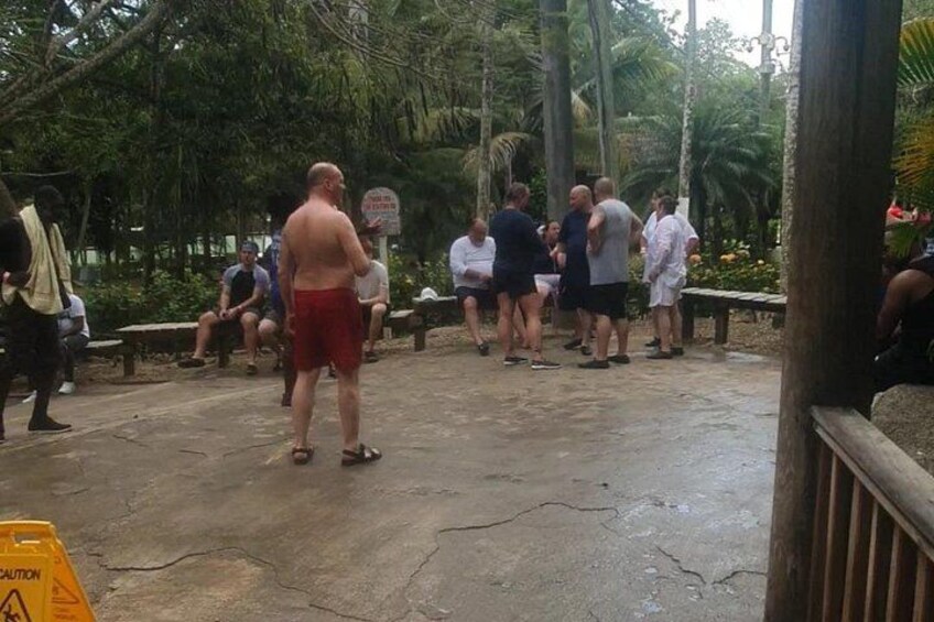 A group of people standing and sitting outdoors, possibly at a park or public gathering area. 3