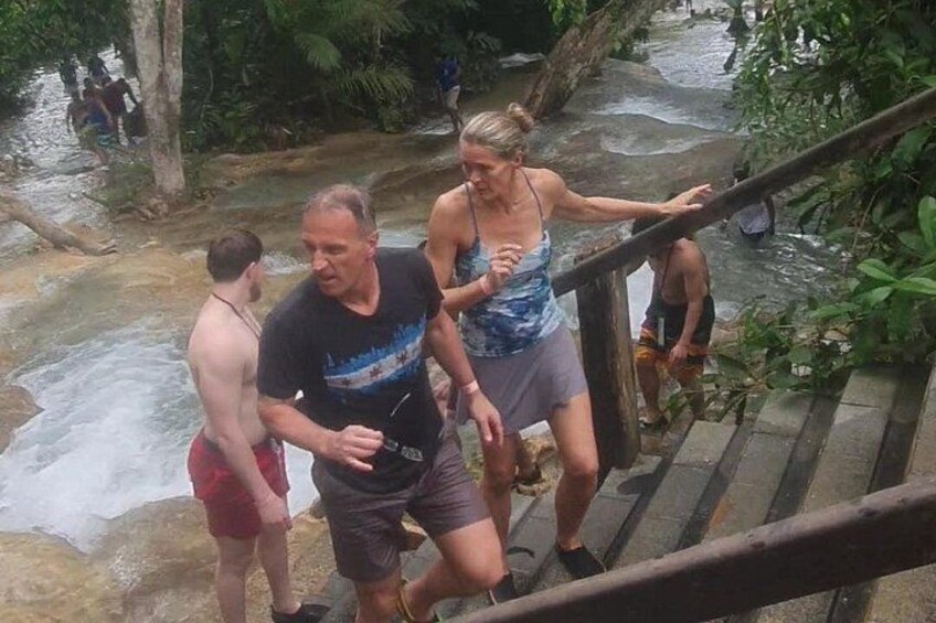 A person descending a wooden staircase in a natural setting with a stream and greenery in the background. 5