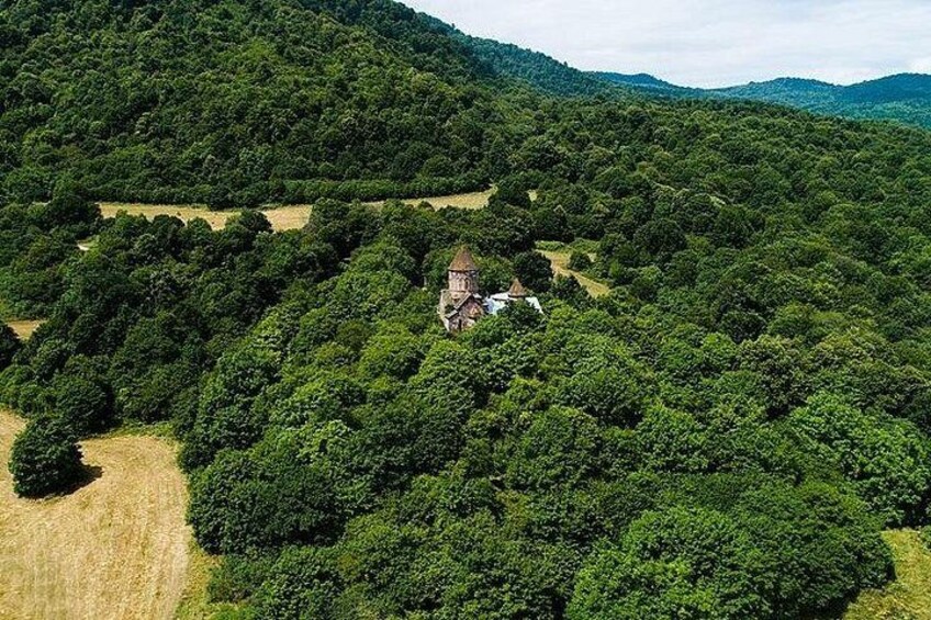 A rural landscape with a house surrounded by dense forest and rolling hills. 3