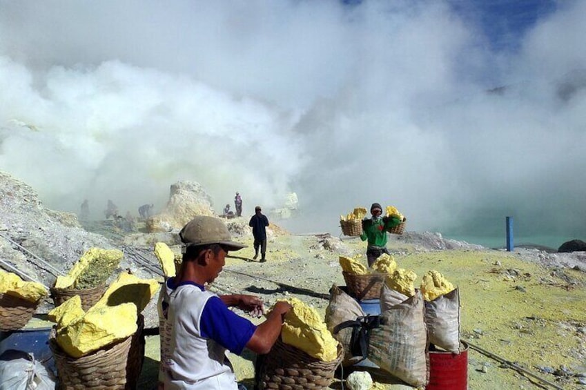 People working in a dusty, mountainous area with bags of material. 5