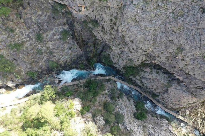 Une rivière qui traverse un défilé rocheux et où se trouve un pont en bois. 5