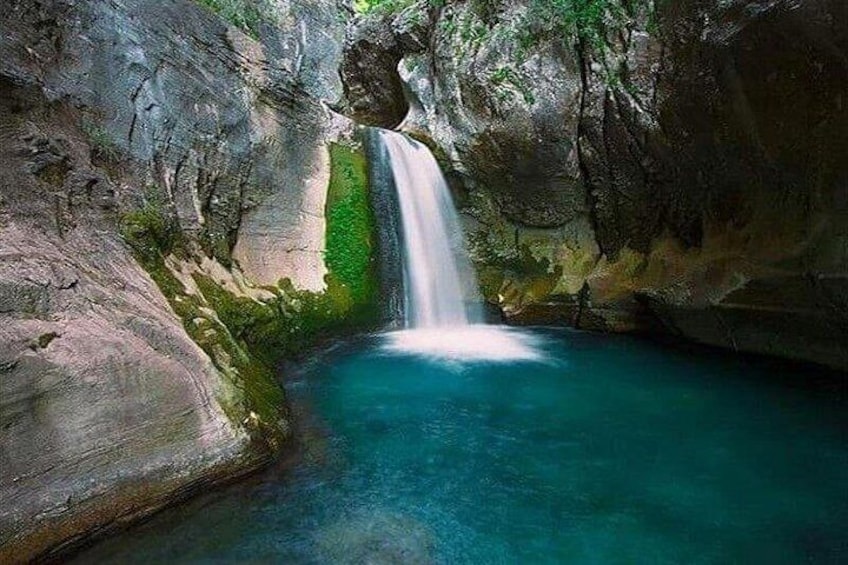 Une cascade se jetant dans un bassin turquoise, entouré de falaises rocheuses. 2