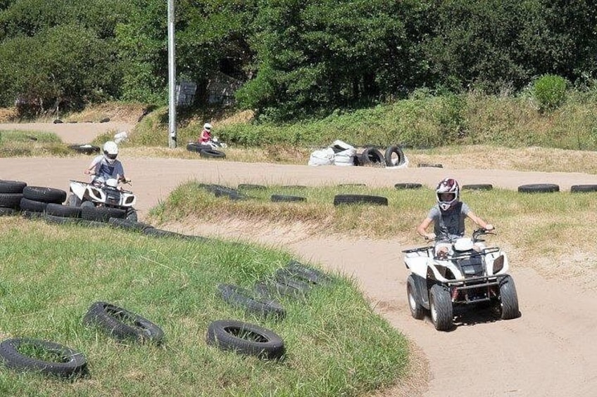 A dirt track with off-road vehicles, tires, and a person riding a quad bike. 3