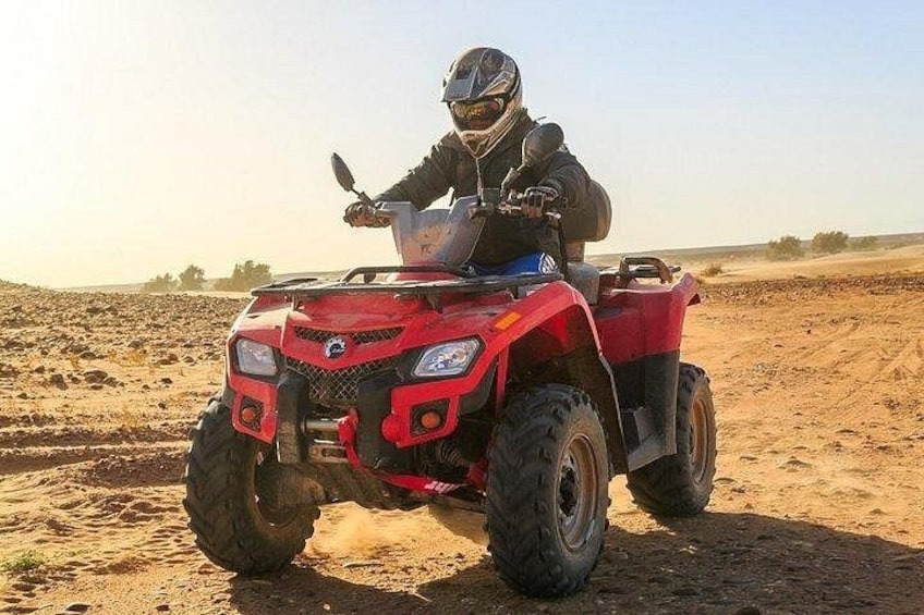 A person riding a red quad bike on a sandy terrain. 2