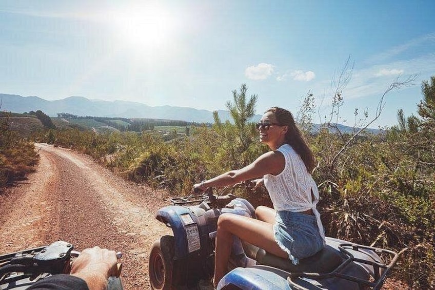 A person riding a quad bike on a dirt road with a mountainous landscape in the background. 5