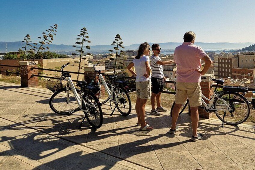 Un grupo de personas en una terraza con vistas a un paisaje urbano, con bicicletas estacionadas cerca. 2