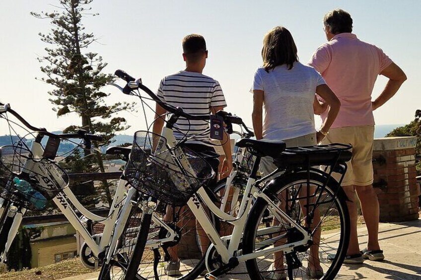Un grupo de personas de pie junto a bicicletas cerca de la costa, con vista al océano. 1