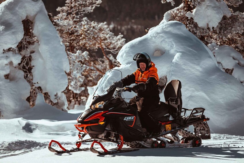 A person riding a snowmobile on a snowy landscape with trees. 4