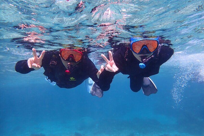 Two scuba divers underwater making peace signs. 5