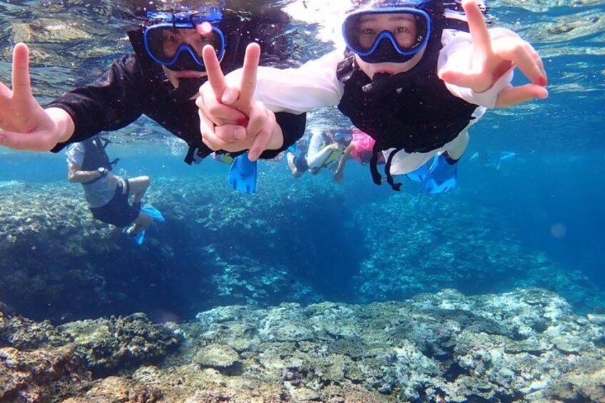 Two people scuba diving underwater, pointing at the camera. 3