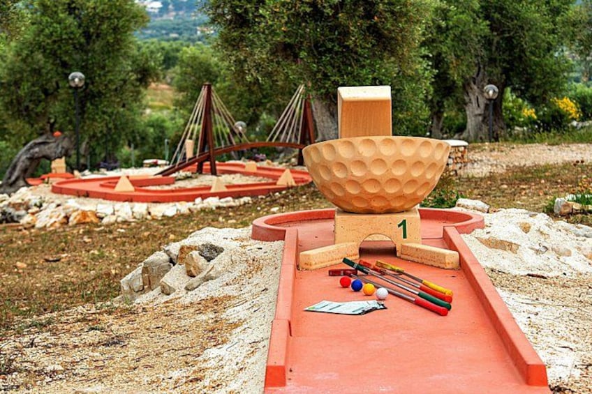 A playground with a red slide, a wooden bowl, and various toys. 1