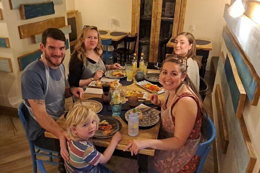 A family dining at a wooden table with various dishes and drinks. 5