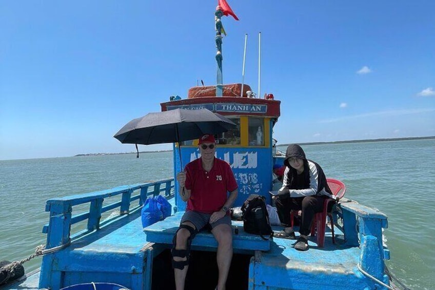 A boat with a blue and yellow structure, a person in a red shirt, and another person in a black jacket. 3