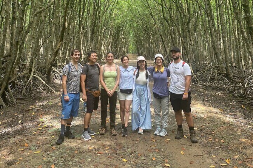 A group of people standing on a forest path surrounded by trees. 1