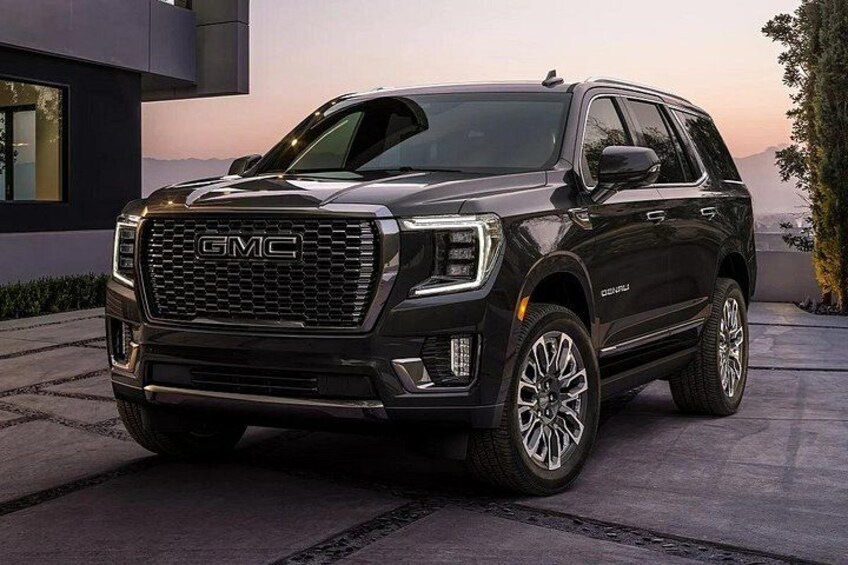 A GMC SUV parked on a driveway with a modern house in the background. 3