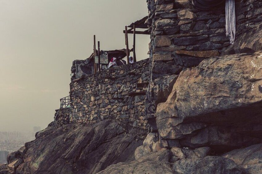 A stone structure with a wooden staircase and a flag. 1