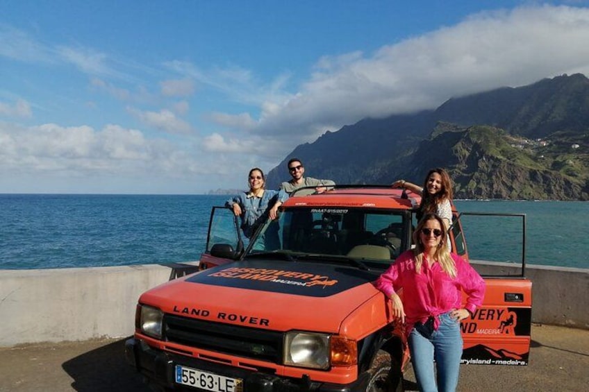 Un Land Rover rojo estacionado junto al mar, con gente alrededor. 3