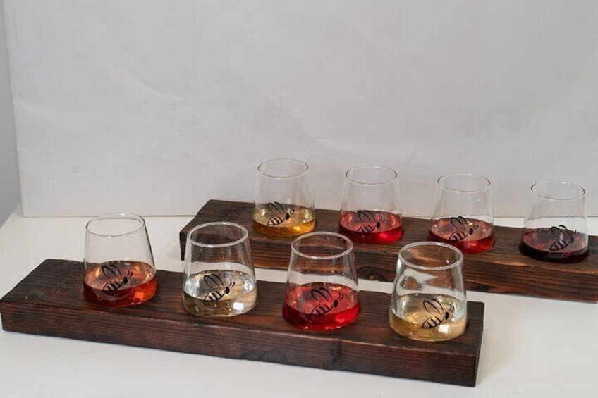Six glasses of varying colors on a wooden tray. 5