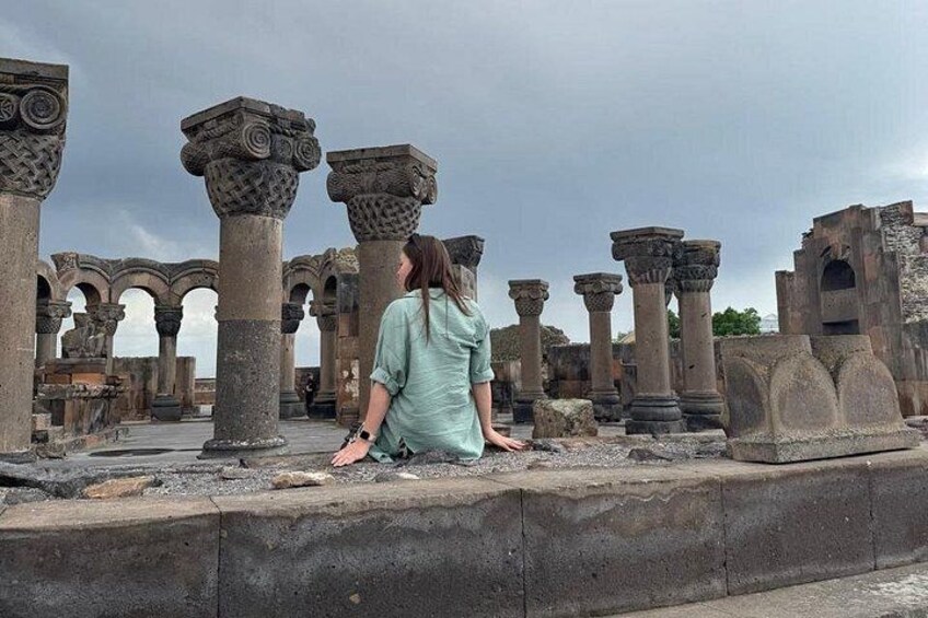 A person sitting among ancient stone columns and arches. 1
