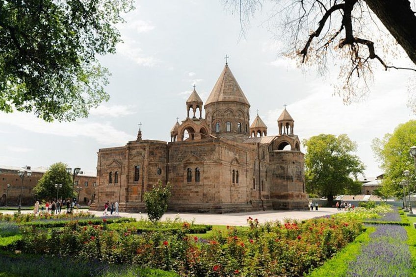 A historic church with multiple domes and bell towers, surrounded by a well-maintained garden with various plants and flowers. 2