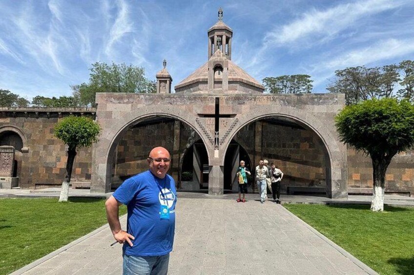 A man standing in front of a church with a bell tower and arched entrance. 3