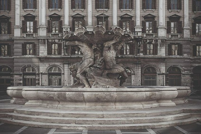 A classical fountain with a sculpture of a horse and rider in front of a building with arched windows and columns. 2
