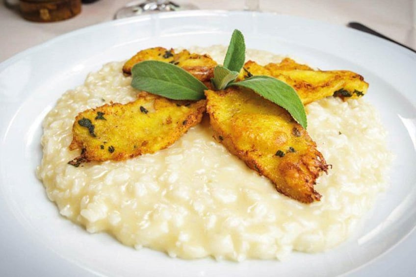 Une assiette de nourriture composée d’une base crémeuse et d’aliments frits dorés, le tout agrémenté de feuilles vertes. 5