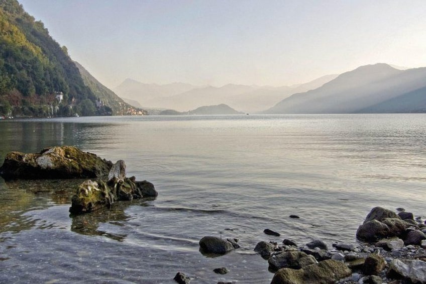 Un lac paisible aux rives rocheuses, avec des montagnes lointaines et un ciel dégagé. 4