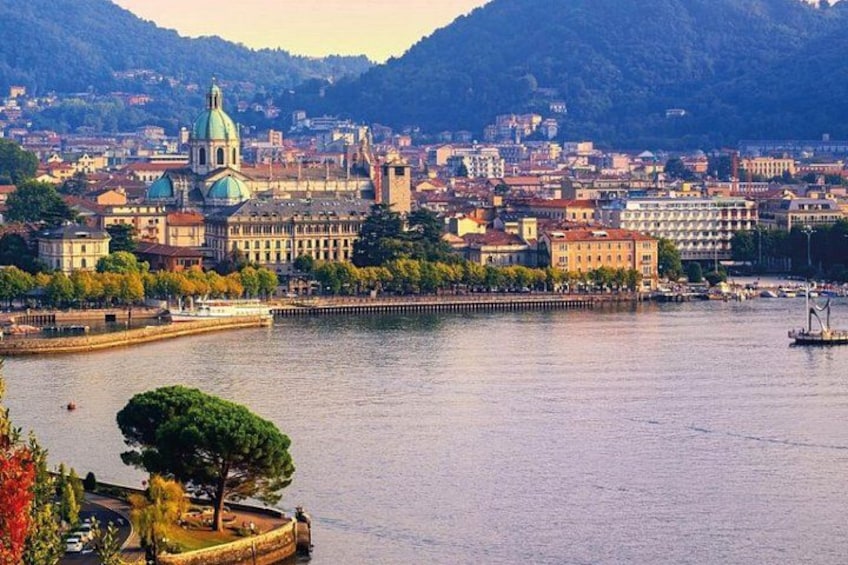 Une vue urbaine avec une église imposante, une rivière et des montagnes en arrière-plan. 1