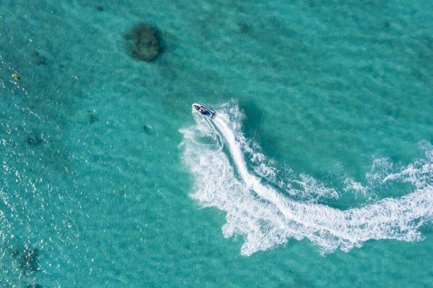 A boat creating a wake in turquoise water. 2