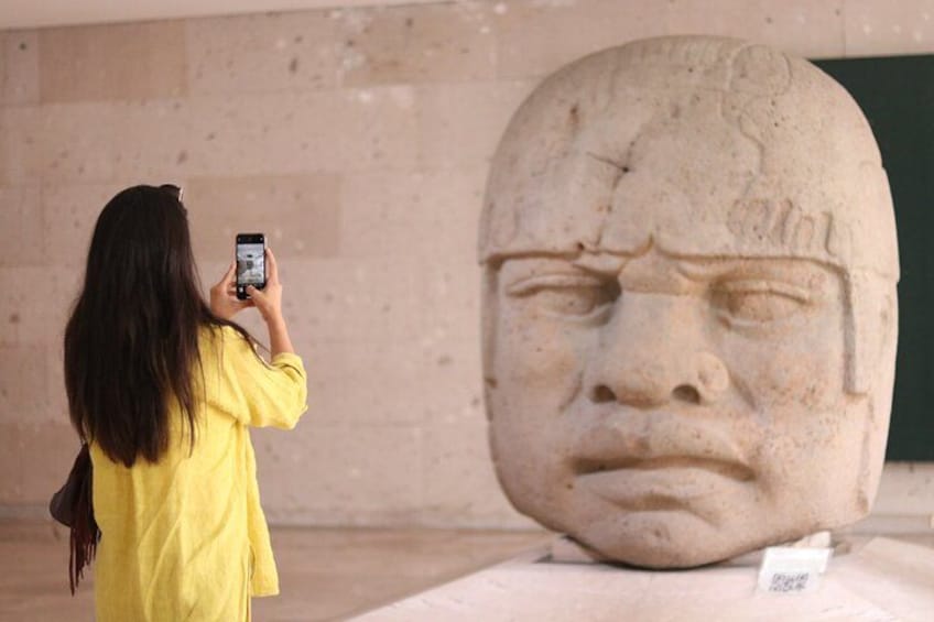 A person taking a photo of a large stone sculpture. 5