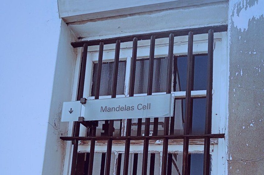 A building with a sign reading 'Mandelas Cell' and barred windows. 3